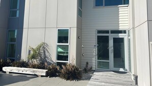 Een modern gebouw met grote ramen, een bankje en een kleine tuin.