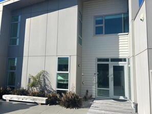 Un bâtiment moderne doté de grandes fenêtres, d’un banc et d’un petit espace aménagé en jardin.