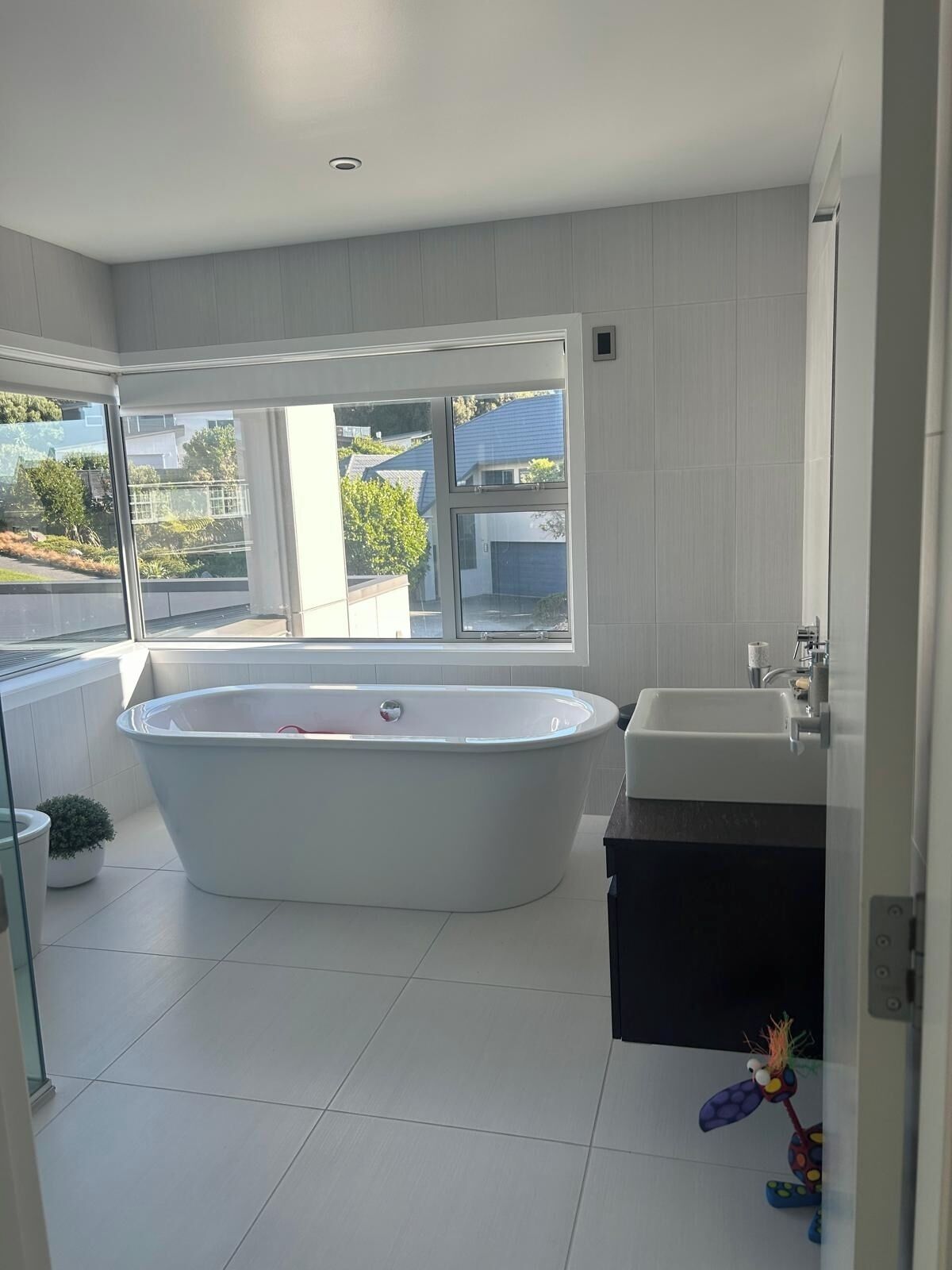 Une salle de bain moderne avec une baignoire sur pieds, un lavabo et une grande fenêtre donnant sur l’extérieur.