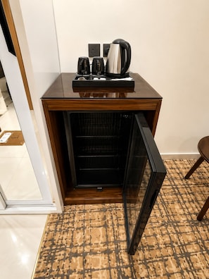 A kitchenette with a coffee maker, two cups, and a kettle.