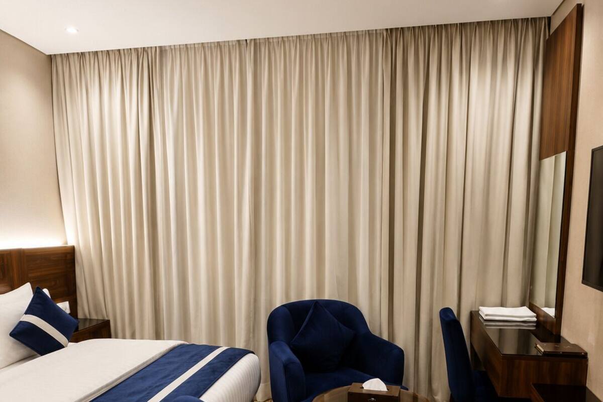 Una habitación de hotel con una cama grande, un escritorio, una silla y una pequeña mesa.