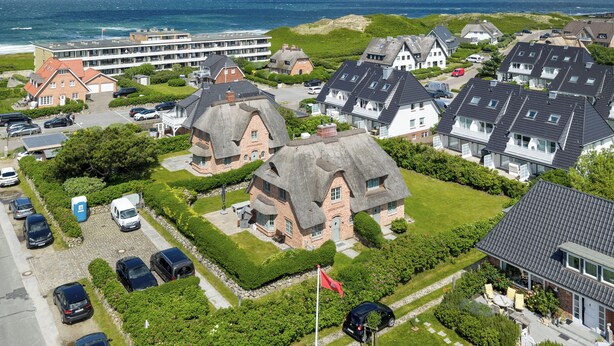 A coastal residential area with houses, a parking lot, and a view of the sea. - Wääfblik – Your vacation home on Sylt with a sauna and ocean view (Wenningstedt-Braderup (Sylt))
