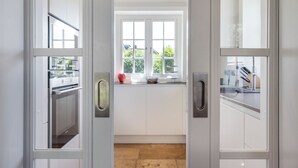 A modern kitchen with white cabinets, a window, and a view of the outdoors. - Wääfblik – Your vacation home on Sylt with a sauna and ocean view (Wenningstedt-Braderup (Sylt))