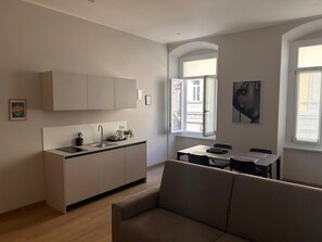 Eine moderne Wohnung mit Küchenzeile, Essbereich und einer Couch.