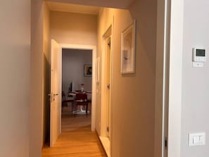 Ein Flur mit Holzboden, ein Essbereich im Hintergrund und ein Thermostat an der Wand.