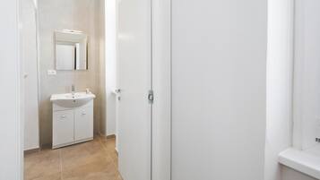 Casa de banho com lavatório branco, espelho e porta.