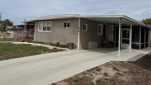 Ett enplanshus med en inglasad veranda, en ytterdörr och en liten trädgård framför huset.