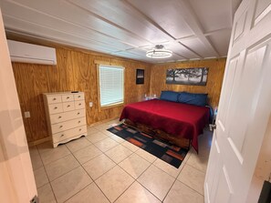 A bedroom with a bed, dresser, window, and ceiling fan.