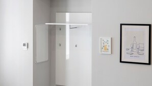 Un bagno moderno con box doccia bianco, un'opera d'arte incorniciata a parete e un interruttore della luce.