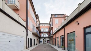 Un vicolo pedonale tra edifici, con un portone di garage a sinistra e un negozio a destra.