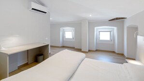Una camera da letto minimalista con un letto, un comodino e un piccolo angolo studio.