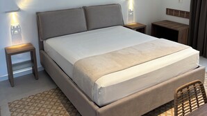 Habitación de hotel ordenada con una cama grande, mesitas de noche con lámparas, un elemento decorativo en la pared y un suelo con diseño.