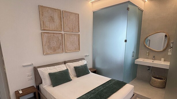 Un dormitorio con cama, mesitas de noche, armario, espejo y una alfombra estampada.