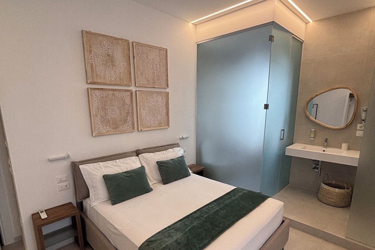 A bedroom with a bed, bedside tables, a wardrobe, a mirror, and a patterned rug.