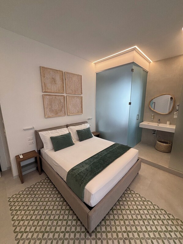 A bedroom with a bed, bedside tables, a wardrobe, a mirror, and a patterned rug.