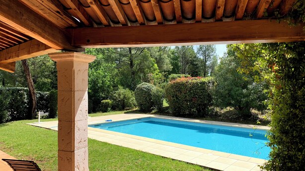 A covered patio area with a pool, a table with chairs, and a stone pillar. - Villa with a private pool (Fayence)