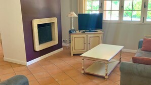 A living room with a sofa, a television, a small cabinet, and a window with curtains. - Villa with a private pool (Fayence)