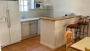 A kitchen with white cabinets, a microwave, a sink, and a dining area with chairs. - Villa with a private pool (Fayence)