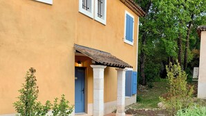 A building with a yellow facade, blue shutters, and a pathway leading to a door. - Villa with a private pool (Fayence)