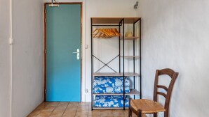 A room with a blue door, a wooden chair, and a shelving unit with folded clothes.