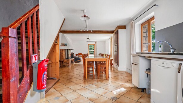 A spacious kitchen with a dining area, a fire extinguisher, and a view of the outdoors.