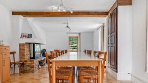 A dining area with a long table and chairs, a fireplace, and a view of the outdoors.