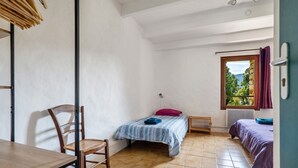 A small, sparsely furnished room with a bed, a chair, and a table.
