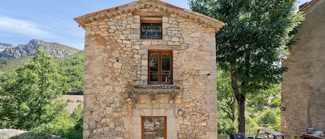 A stone building with a wooden door, a small window, and a balcony.