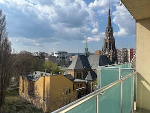 A view of a cityscape with a prominent church spire, a yellow building, and modern high-rise buildings. - OB44 Apartments Budapest (Budapest)