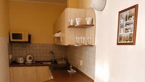 A compact kitchen with a wooden bar counter, stools, a microwave, and a sink.