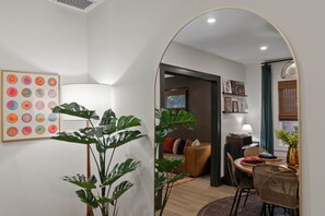 A modern living room with a dining area, a large plant, and a colorful abstract painting on the wall. - Welcome to Sue Zen Urban Retreat — Grandview Heights, Columbus (Grandview Heights)