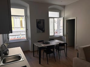 Een moderne keuken met een eetgedeelte, grote ramen en een flatscreen televisie.