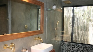 A bathroom with two sinks, a large mirror, and a shower.
