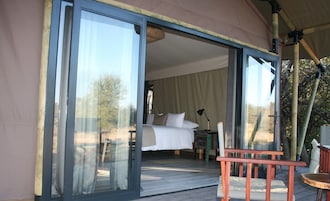 Una habitación con cama, una silla y una mesa, con vista al exterior a través de una puerta de vidrio.