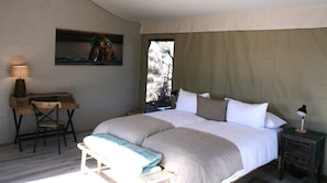 Une chambre à coucher avec un lit, un bureau, une chaise, une lampe et un tableau au mur.
