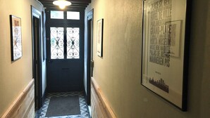 En hall med ett mönstrat golv, en dörr med dekorativt glas och inramade affischer på väggarna.