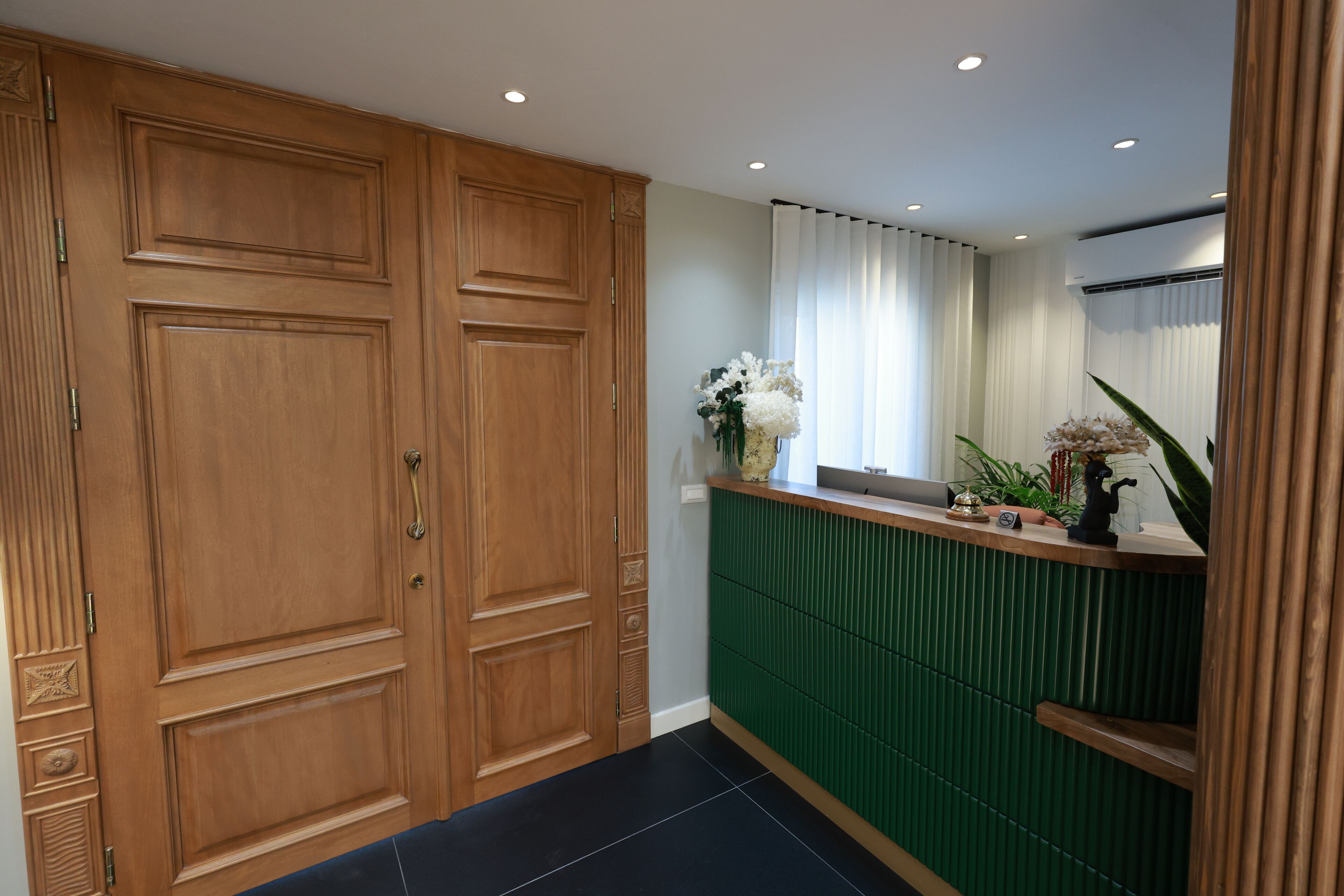 Una habitación con un armario de madera, una pared verde de acento y una ventana con cortinas blancas.