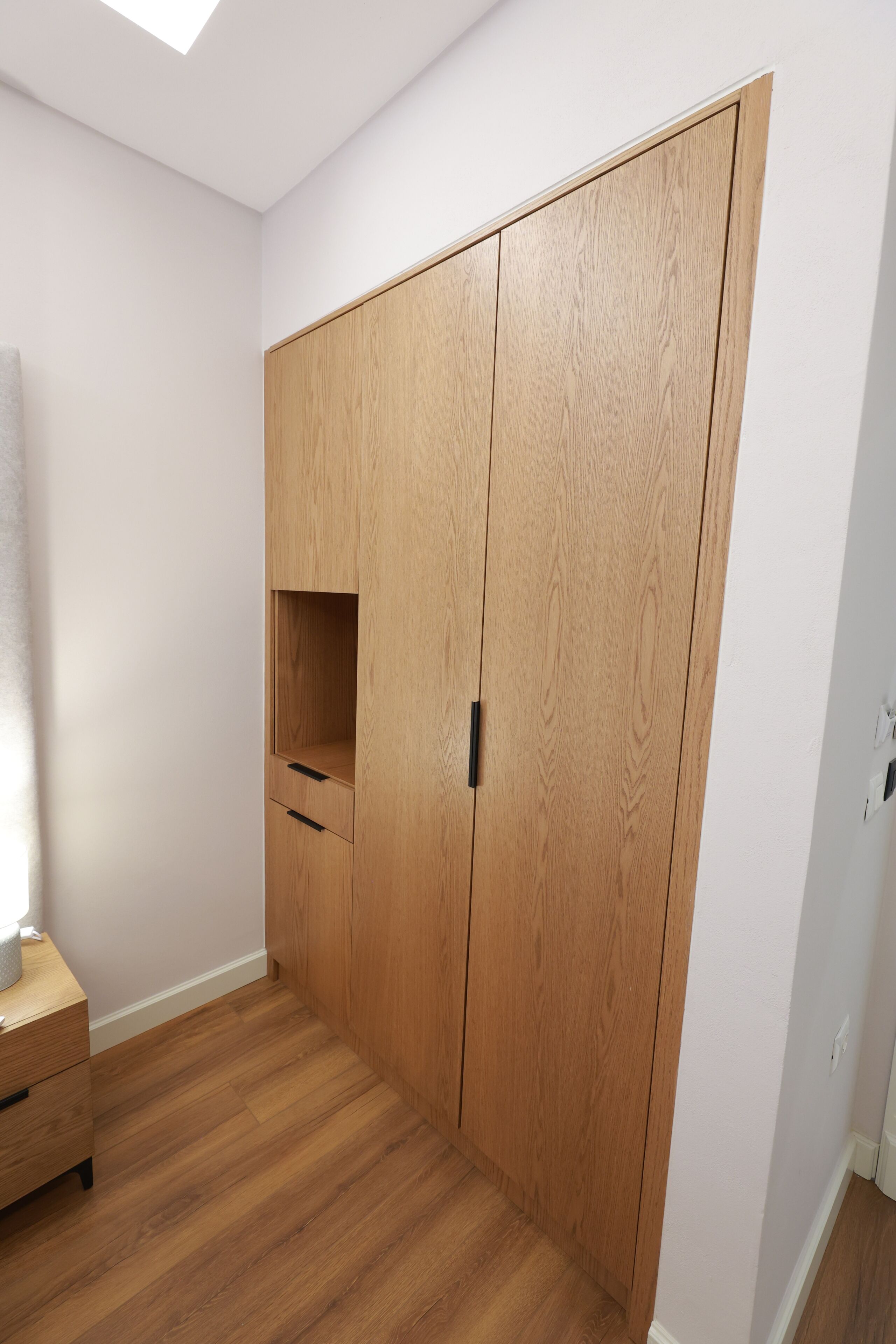 A room with a wooden wardrobe, a small wooden cabinet, and a wooden floor.