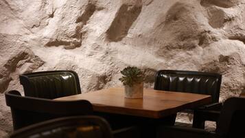 En restaurant med en baggrund af stenvæg, et træbord og læderstole.