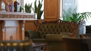 Una habitación con sofá capitonado, paneles de madera y plantas en macetas.