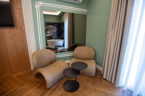 A modern room with a wooden floor, a large mirror, a bathtub, and two round tables. - Voko by Uka Boutique Hotel (Tirana)