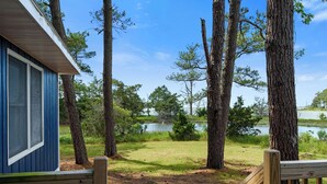 Une terrasse en bois qui mène à une maison offrant une vue sur un lac et des arbres.