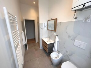 Un baño moderno con un bidé, un lavabo, un espejo y un perchero para toallas.