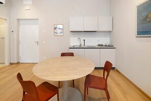 Une cuisine moderne avec des meubles blancs, une table ronde entourée de chaises et un tableau accroché au mur.