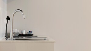 Een moderne keuken met een roestvrijstalen kraan, een koffiezetapparaat en een waterkoker op het aanrecht.