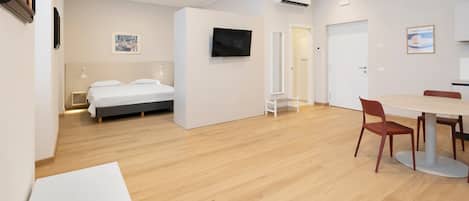 Une chambre d’hôtel moderne équipée d’un lit, d’une télévision, d’un coin repas avec des chaises et d’une petite table.