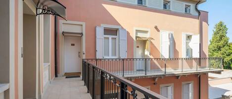 A multi-story building with balconies, a door, and a window with shutters.