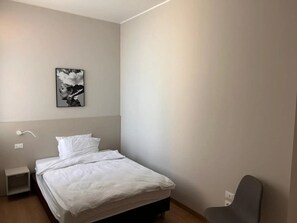 A bedroom with a bed, a nightstand, a chair, and a wall-mounted light. - 'Gorizia' Apartment with Wi-Fi and Air Conditioning (Gorizia)