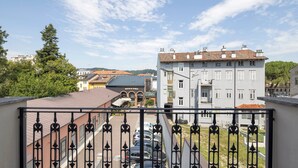 En balkon med jerngitter og udsigt over en parkeringsplads og bygninger.