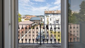 En balkon med jerngitter, udsigt til bygninger og en klar himmel.